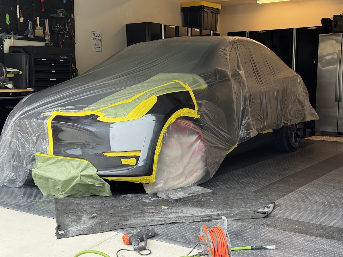 Tesla Model Y masked in plastic and tape for front bumper and fender paintwork
