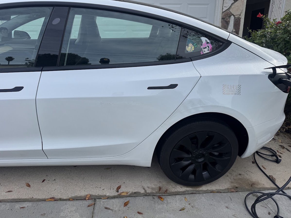Long horizontal scratch across the rear door and quarter panel of a white Tesla Model 3