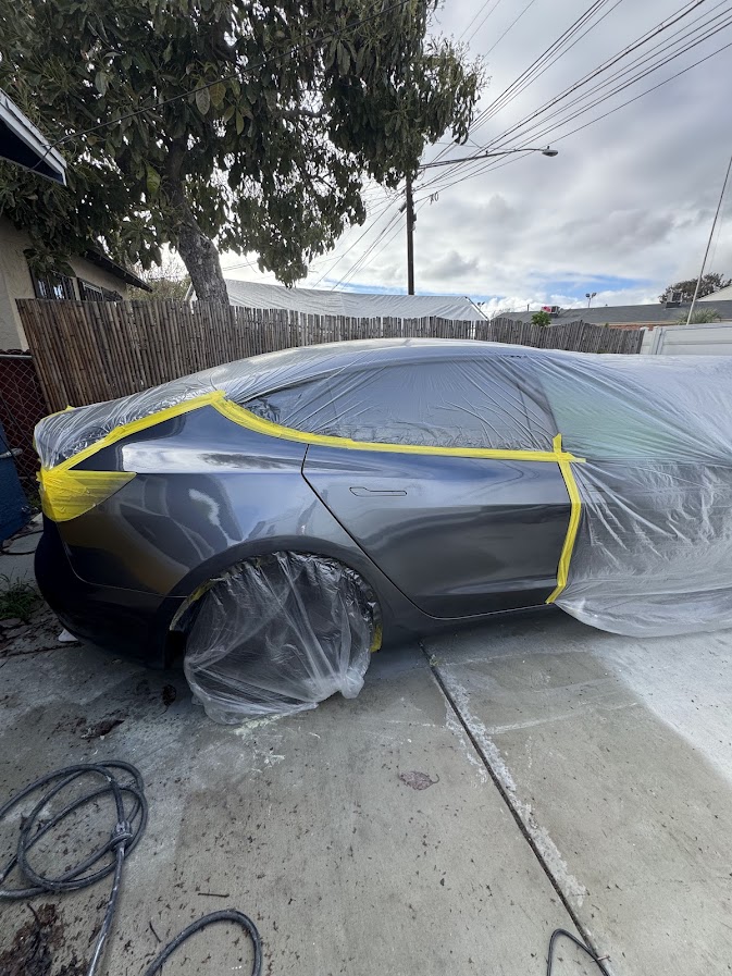 Tesla Model 3 masked in plastic for rear quarter panel paintwork