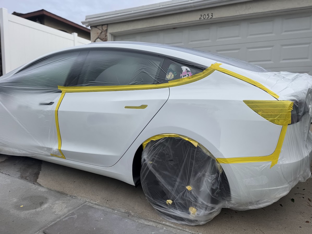 White Tesla Model 3 masked off for rear door and quarter panel painting