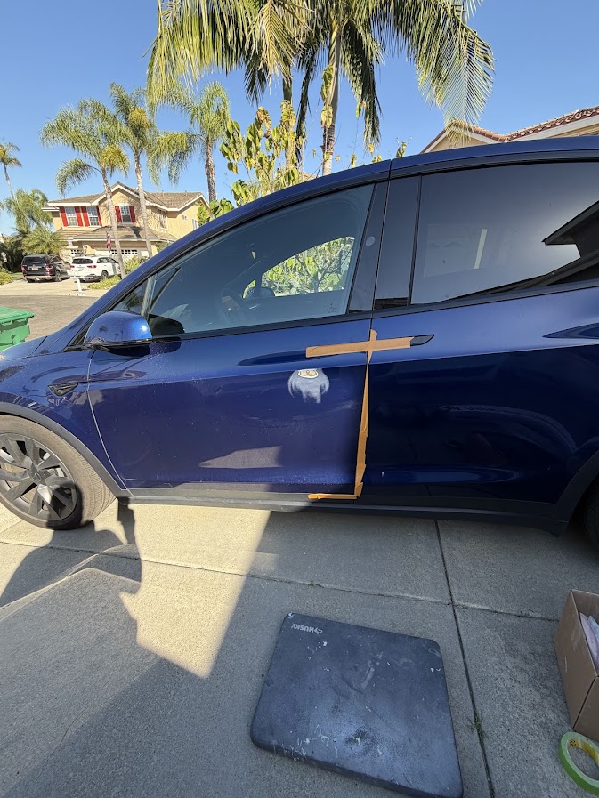Sanded and primed repair spot on a Deep Blue Tesla Model Y door
