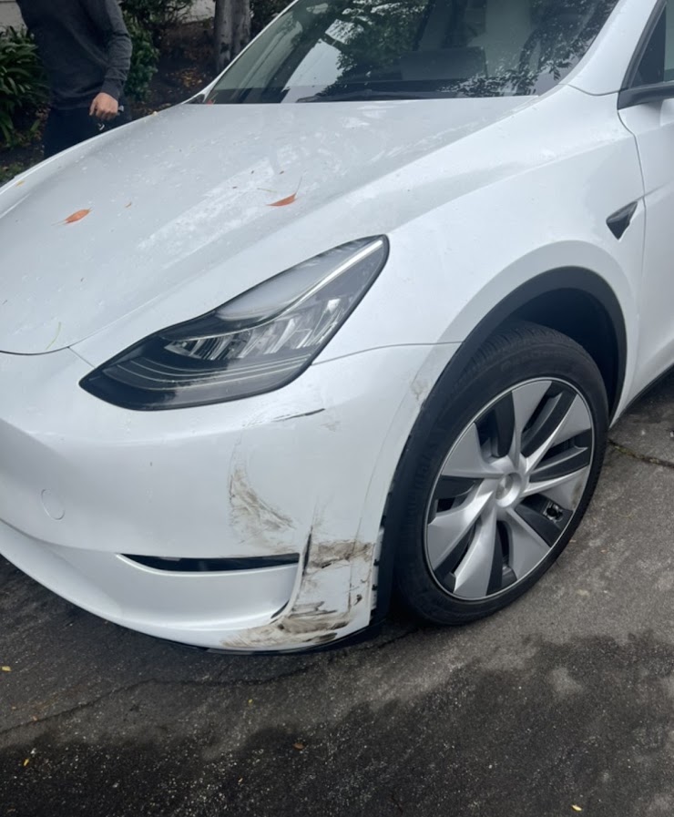 White Tesla Model Y lower front bumper and wheel arch trim with deep gouges
