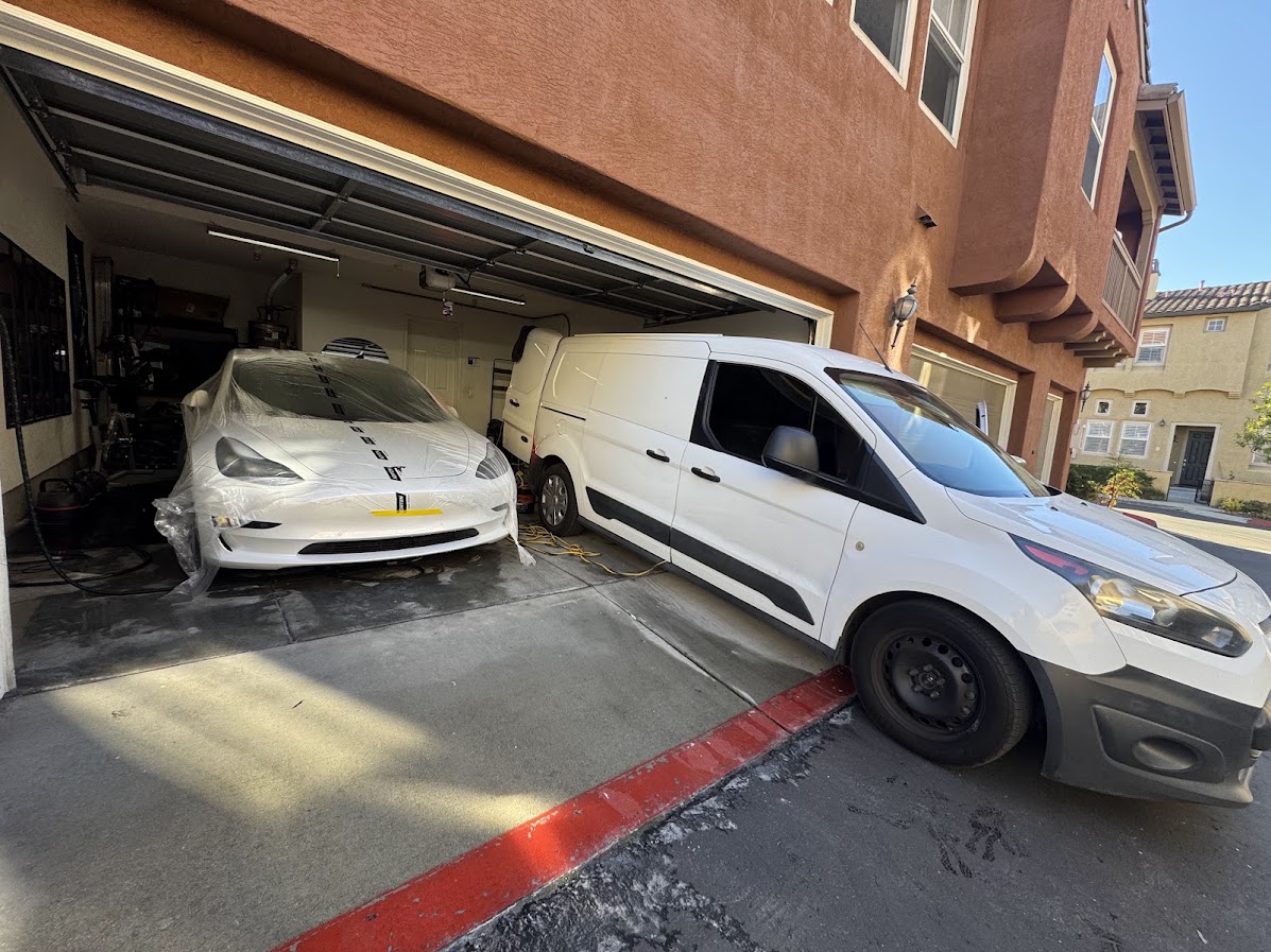 Tesla masked for paintwork inside a garage with the service van outside