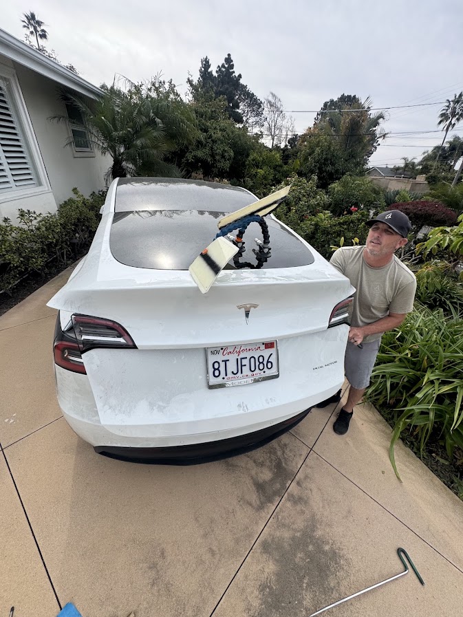Paintless dent repair on a white Tesla Model Y tailgate using a PDR light board