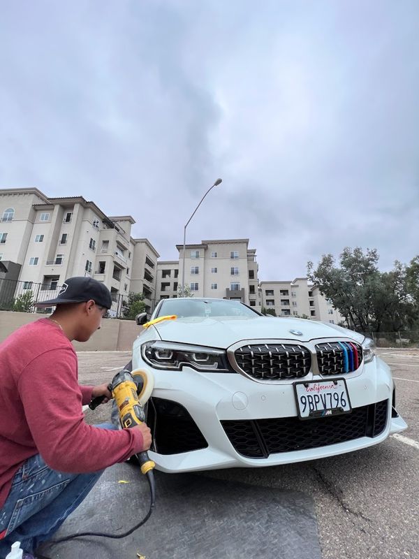 Technician machine-polishing a white BMW M340i bumper